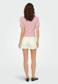 Top rosa a righe con maniche corte abbinato a pantaloni corti bianchi con orlo arrotolato, che mostra un design testurizzato e una vestibilità comoda e facile. Collo regolabile.