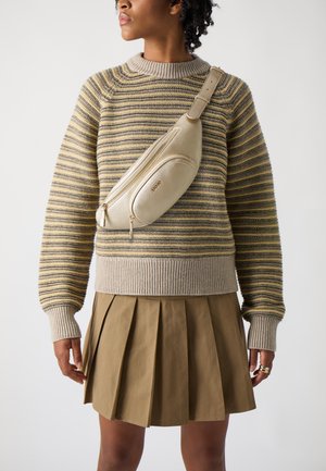 Bolso cruzado beige de cuero texturizado, llevado sobre un suéter de punto a rayas y una falda plisada color caqui, que muestra un diseño moderno y casual.