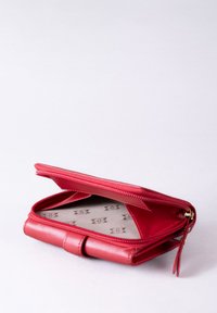 Red leather wallet with zipper closure, featuring a smooth exterior and a patterned fabric lining. Slightly structured design, compact size.