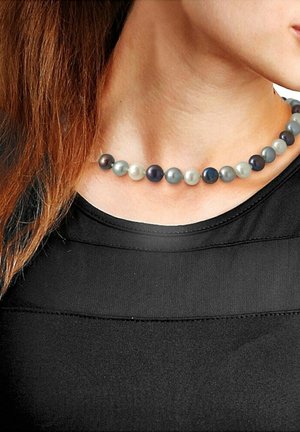 Collier de perles multicolores présentant des perles rondes dans des teintes de gris, noir et blanc avec une texture lisse, porté sur un haut noir.