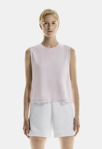 Mouwloos topje van lichtroze stof, ronde halslijn, losse pasvorm, gecombineerd met witte shorts. Gladde textuur, minimaal ontwerp, geen patronen.