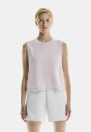 Ärmlös topp i ljusrosa tyg, rund halsringning, lös passform, kombinerad med vita shorts. Slät textur, minimalistisk design, inga mönster.