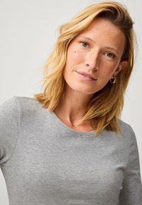 Grijze, lange mouwen, aansluitend shirt van zacht, glad materiaal met een ronde halslijn en minimale textuur.