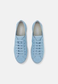 Ljusblå perforerade sneakers med platta snören och en vit gummisula. Har en slät tåhuvud och en märkesinläggssula med text.