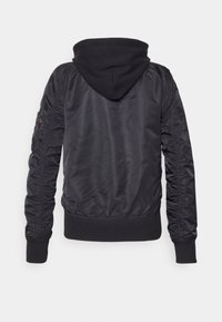 Černá bomber bunda s kapucí, vyrobená z lesklé tkaniny. Má žebrované manžety a lem, a na rukávech je nařasené zdobení. Jednoduchý a elegantní design.