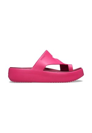 Felroze Crocs slidesandaal met dikke zool en brede band met openingen voor de tenen en de voet, vanaf de zijkant getoond op een witte achtergrond.