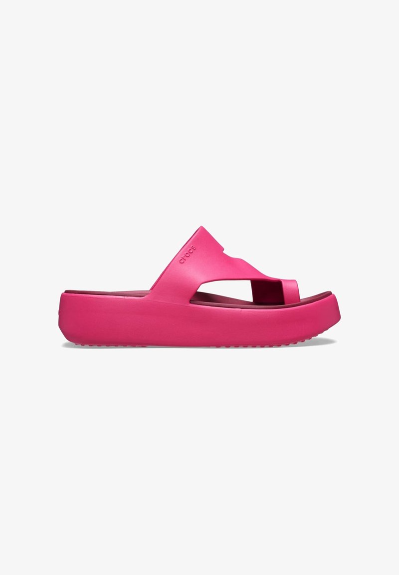 Sandale slide Crocs rose vif avec semelle épaisse et large bride présentant des ouvertures pour les orteils et le pied, vue de côté sur fond blanc.