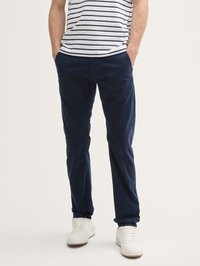 Chinos en coton bleu marine avec poches latérales, coupe droite et texture lisse, associés à un t-shirt rayé gris et blanc et des baskets blanches.