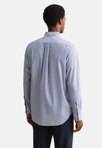 Camicia a righe azzurro chiaro e bianco con bottoni, in cotone, maniche lunghe, taglio sartoriale, piega posteriore, orlo arrotondato, polsini con bottoni.