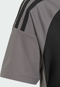 Grijze sportshirt met zwarte accenten, korte mouwen en drie zwarte verticale strepen op de schouder. Gestructureerde stof op de zijpanelen.