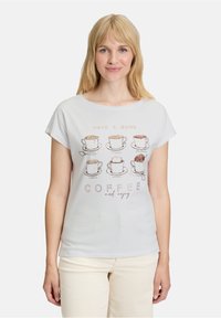 Lysblå bomulds T-shirt med korte ærmer, der har et kaffekop grafik og tekst i en blanding af tryk og kursiv. Enkel og afslappet design.