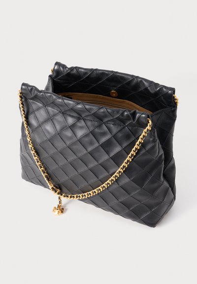 Gequilted zwarte leren handtas met een gouden kettingriem en bedel, met een ruime binnenkant en een drukknoopsluiting.