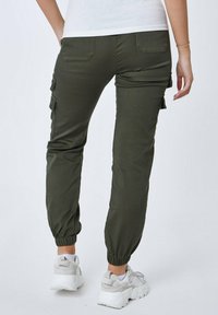 Pantalones cargo verde oliva con puños elásticos, bolsillos laterales y traseros. Fabricados con un tejido duradero para un ajuste cómodo.