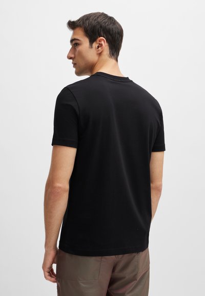 T-shirt noir à manches courtes avec un col rond, fabriqué en coton doux. Texture lisse et design simple sans accents visibles ni motifs.