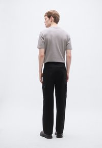 Hall halli lühikeste varrukatega t-särk, mida on kombineeritud mustade küljetaskutega cargo-pükstega. Riietus rõhutab lihtsat disaini ja vabaistuvat lõiget.