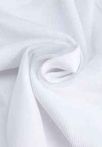 Tissu blanc côtelé torsadé en spirale, montrant la texture et des plis doux en gros plan.