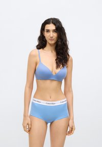 Svetlomodrá podprsenka s nastaviteľnými ramienkami a hlbokým výstrihom, doplnená o svetlomodré nohavičky so znakovaným bielym pásom.