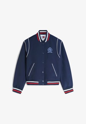 Veste universitaire bleu marine avec col, poignets et bas rayés rouge, blanc et bleu, liseré blanc, fermeture par boutons et écusson brodé sur la poitrine.