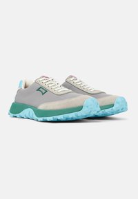 Scarpe sportive con tomaia in tessuto grigio, dettagli verdi e suola in gomma azzurro chiaro con un motivo di battistrada testurizzato.
