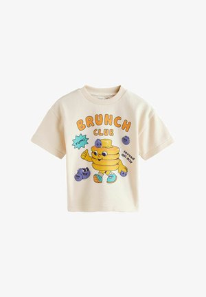 Beiges Kurzarm-T-Shirt für Kleinkinder mit Cartoon-Pfannkuchen, die Turnschuhe tragen, Blaubeeren und dem Text "BRUNCH CLUB serviert den ganzen Tag" und "LECKER!"