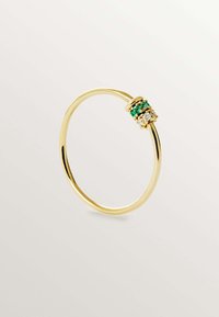 Anillo de oro con un conjunto de gemas verdes y transparentes, diseñado de forma minimalista con una banda circular y lisa.