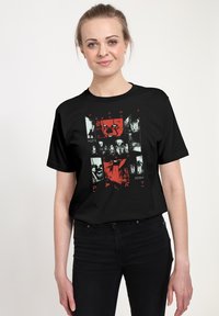 Czarny t-shirt z krótkim rękawem z graficznym nadrukiem w czerwonych i białych kolorach, przedstawiający elementy i teksty w tematyce horroru.
