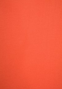 Tissu orange uni texturé avec un motif tissé visible et une répartition uniforme de la couleur.