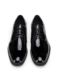 Zapatos de vestir de charol negro con un acabado suave y brillante, que presentan un diseño clásico de cordones y una forma de punta afilada.