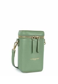 Borsa a tracolla verde in pelle con forma cilindrica, zip dorata e logo del marchio. Presenta una tracolla rimovibile e una finitura testurizzata.