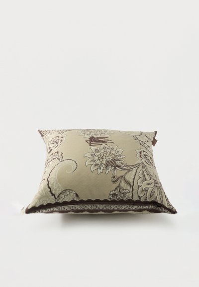 Coussin décoratif beige avec des motifs floraux complexes marron et des motifs cachemire sur un fond blanc uni.