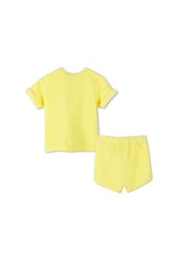 Geel katoenen twee-delige outfit bestaande uit een t-shirt met korte mouwen en omgeslagen mouwen, en bijpassende shorts met een elastische tailleband.