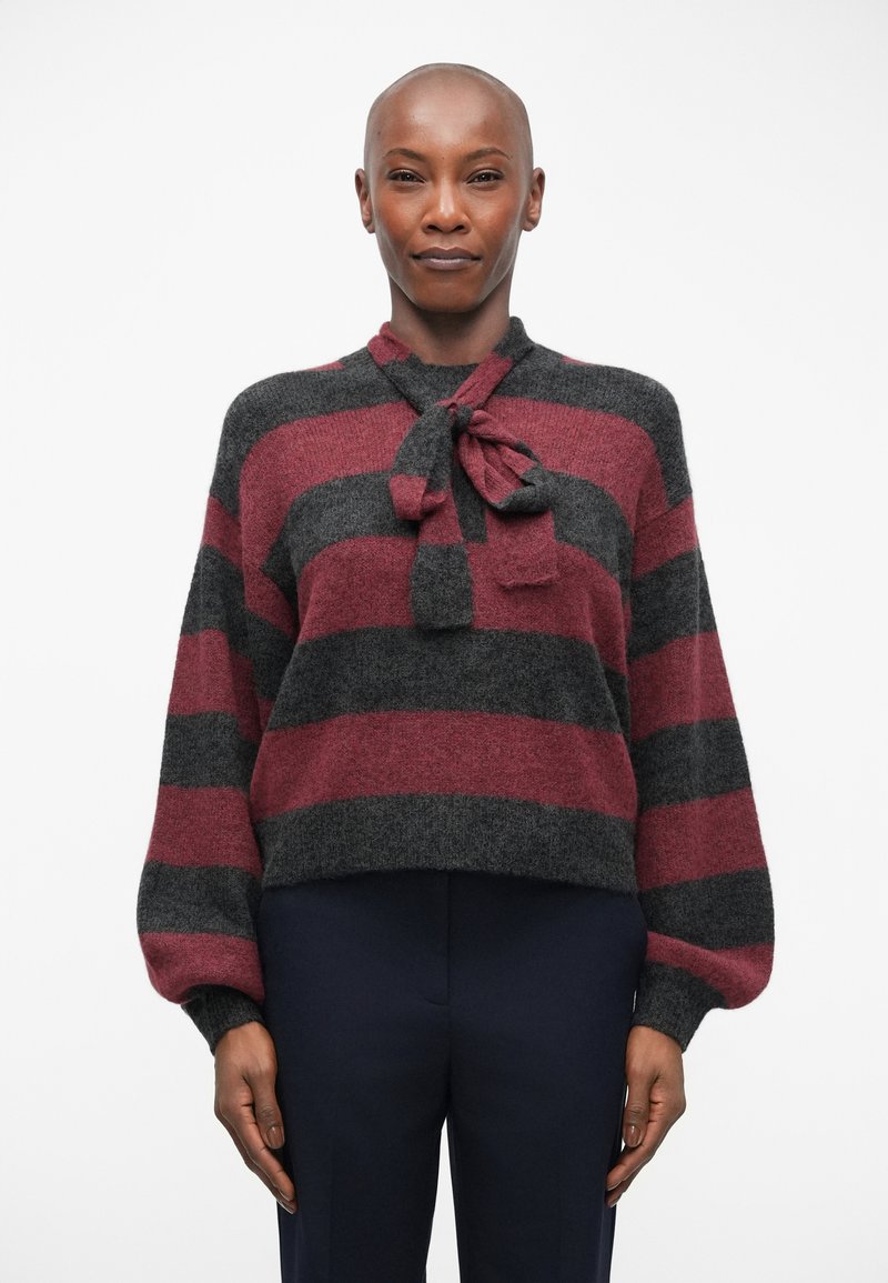 Pull rayé en gris foncé et bordeaux, doté d'un col à nouer, de manches longues et d'une coupe cropped. Texture douce, avec de larges rayures sur l'ensemble.