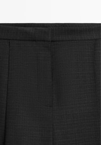 Black trousers with a textured pattern, featuring a structured waistband and front pleats for a tailored design.
