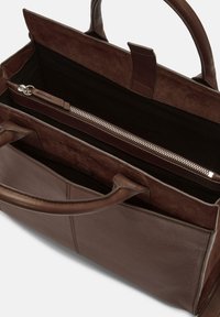 Brązowa skórzana torba na ramię o gładkiej powierzchni, solidnymi uchwytami i zasuwaną kieszenią w środku. Pluszowe wykończenie dodaje tekstury i głębi.