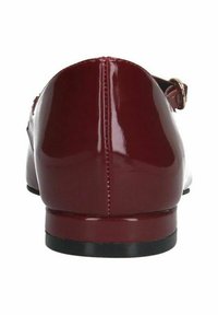 Chaussures en cuir verni bordeaux avec un dos arrondi, un petit talon noir et une sangle réglable maintenue par une boucle en ton doré.