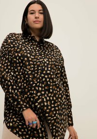 Camicia nera con bottoni, caratterizzata da un motivo a stampa leopardata in marrone e crema, con maniche lunghe e orlo curvo.