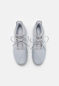 Vaaleanharmaat urheilujalkineet, joissa on verkkopaneelit, litteät nauhat ja teksturoidut pinnat, valkoisella kumipohjalla ja huomaamatomalla brändäyksellä.