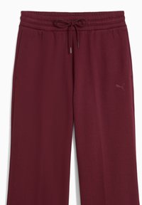 Burgundy joggerbukser lavet af blødt stof, med elastisk talje med snor, sidelommer og en lille logo detalje.