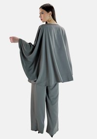 Grau, fließendes Zweiteiler-Outfit mit weiten Ärmeln und lockeren Hosen, gefertigt aus einem glatten, leichten Stoff. Keine auffälligen Muster oder Akzente.
