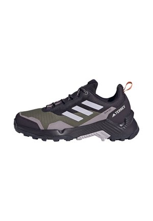 Zwart en olijfgroen sportshoe met een gestructureerde mesh bovenkant, grijze accenten, drie witte strepen en een robuuste zool voor grip.