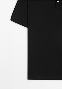 Polo noir à manches courtes avec deux boutons blancs et texture en tissu côtelé sur fond blanc.