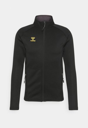 Schwarze Fleecejacke mit hohem Kragen, durchgehendem Reißverschluss, Seitentaschen und gelbem Logo auf der Brust. Glatte Textur, taillierte Passform.