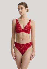 Rød blondebralette med blomstermønster og dyb udskæring, parret med matchende højtaljede blondebikini. Glat stofstruktur.