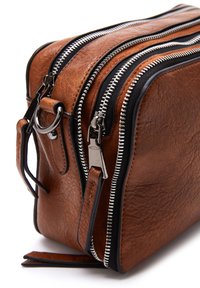 Borsa in pelle marrone con finitura testurizzata, caratterizzata da numerosi zipp neri, accessori in argento e una tracolla rimovibile. Forma rettangolare compatta.