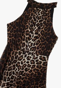 Robe à imprimé léopard avec un mélange de textures brunes et noires, dotée d'un design plissé et d'un col halter. Gros plan sur le tissu et les motifs.