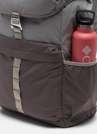 Grey and brown backpack side pocket holding a red water bottle with black cap and white logo.