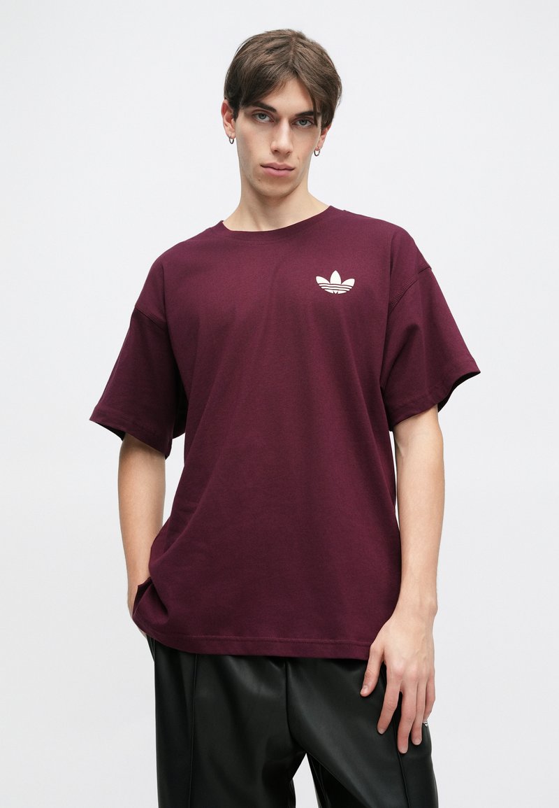 Camiseta de algodón de manga corta color burdeos, con un logo blanco en el lado izquierdo del pecho y un diseño de corte relajado.