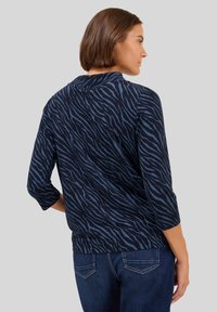 Top blu navy con motivo a righe di tigre, realizzato in materiale morbido, con maniche a tre quarti e scollatura rotonda.