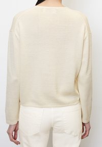 Strickpullover in Hellbeige mit lockerem Schnitt und Raglanärmeln. Glatte Textur mit geripptem Saum und Bündchen.