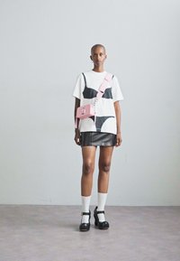 White t-shirt with black bra design, leather mini skirt, pink crossbody bag, black platform shoes, and white socks. Smooth textures throughout.
